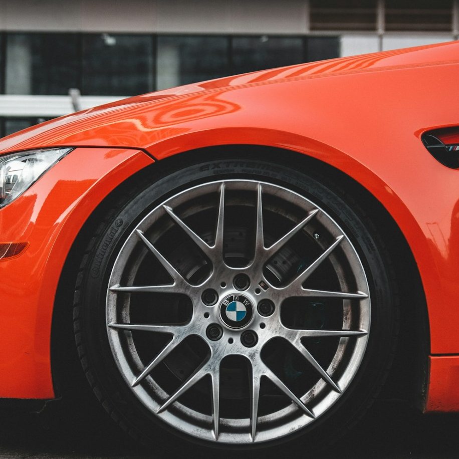 Frisch aufbereitete Felge an einem orange lackierten BMW