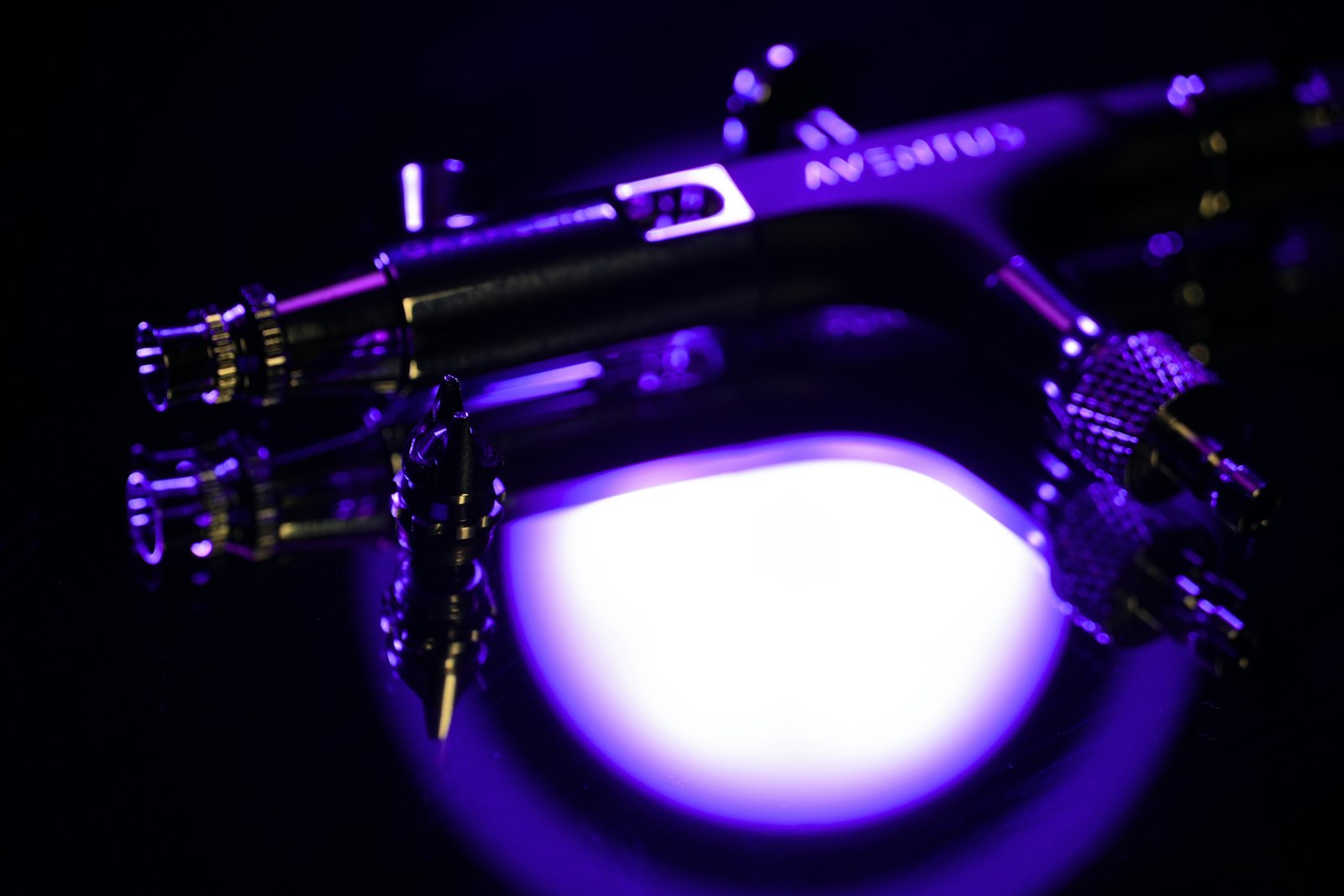 Airbrush-Pistole im farbigen Licht der Lackierkabine