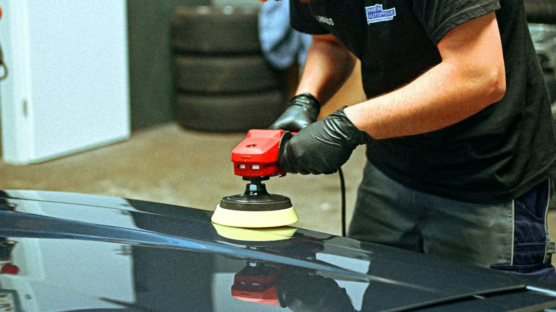 Poliermaschine auf der Motorhaube eines dunklen Fahrzeugs